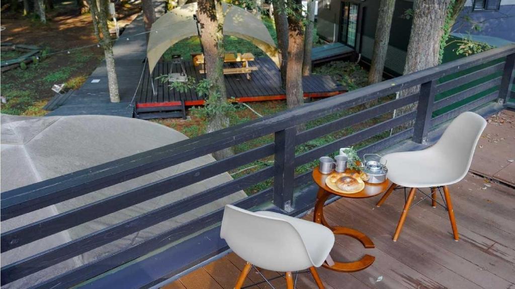 un tavolo e due sedie su un balcone con tavolo e tavolo di Work Shop Camp Resort Forest and Lake Paradise - Vacation STAY 85273v a Fujikawaguchiko