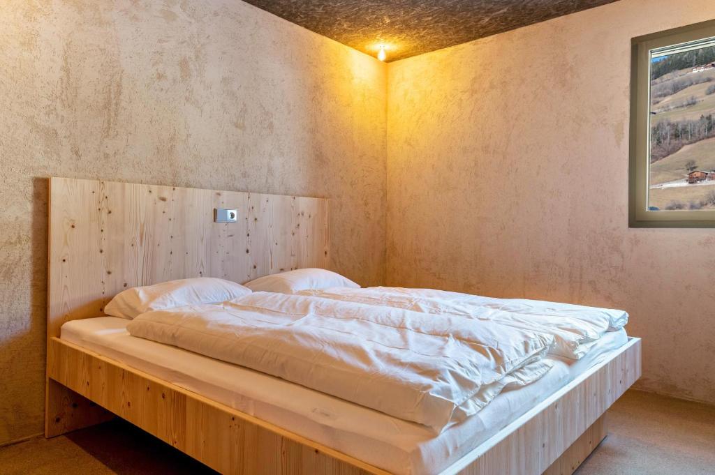 a bedroom with a large bed with a wooden headboard at Lena Dolomites Gartensuite in Villnoss