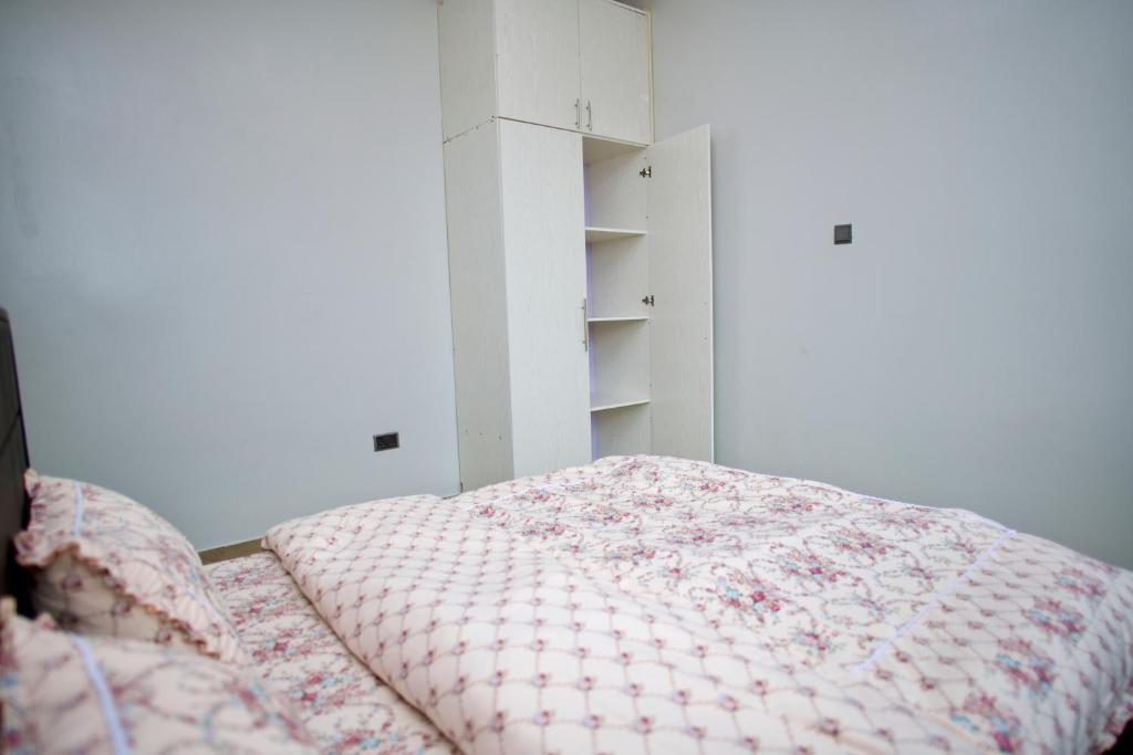 Bett in einem weißen Zimmer mit einer rosa Decke in der Unterkunft ATA Luxe Apartments in Kira