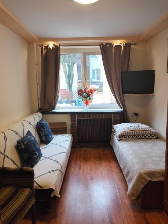 Una sala de estar con un sofá y una ventana. en komfortowy pokój nad morzem, en Kołobrzeg