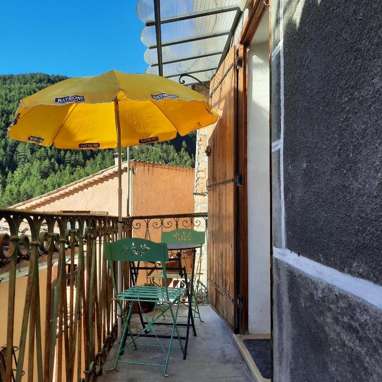 un parasol jaune et deux chaises sur le balcon dans l'établissement le bolca, à Sausses