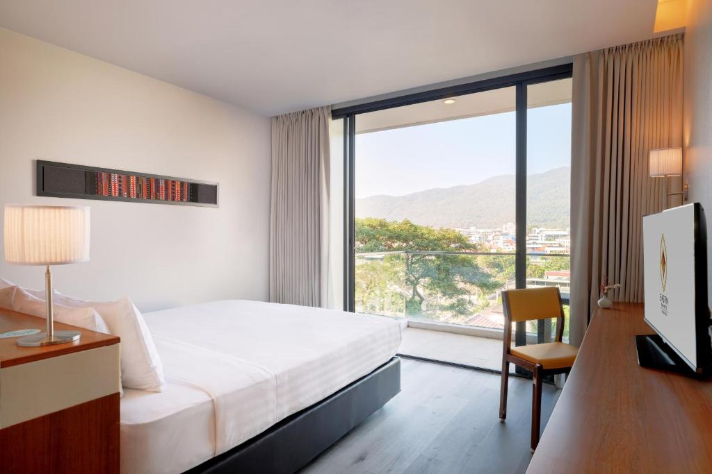 A bedroom arranged around a broad picture window overlooking mountains, trees and the city.