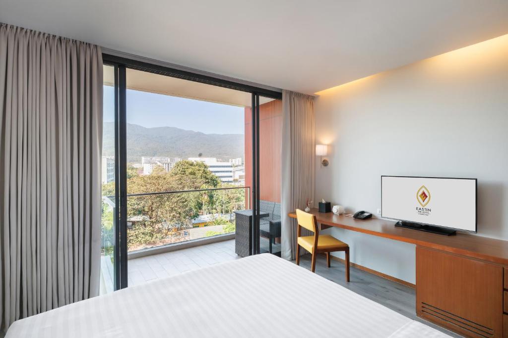 A bright bedroom opening onto a balcony with a mountain view and a full-length work desk.