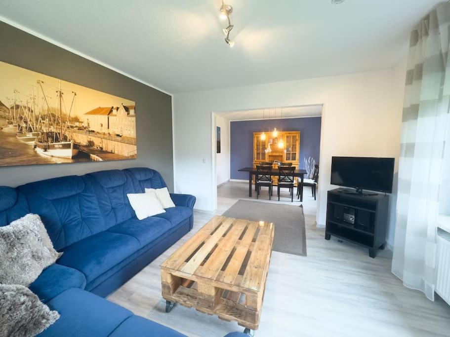 a living room with a blue couch and a wooden coffee table at Haus Glücksfang in Hooksiel in Wangerland