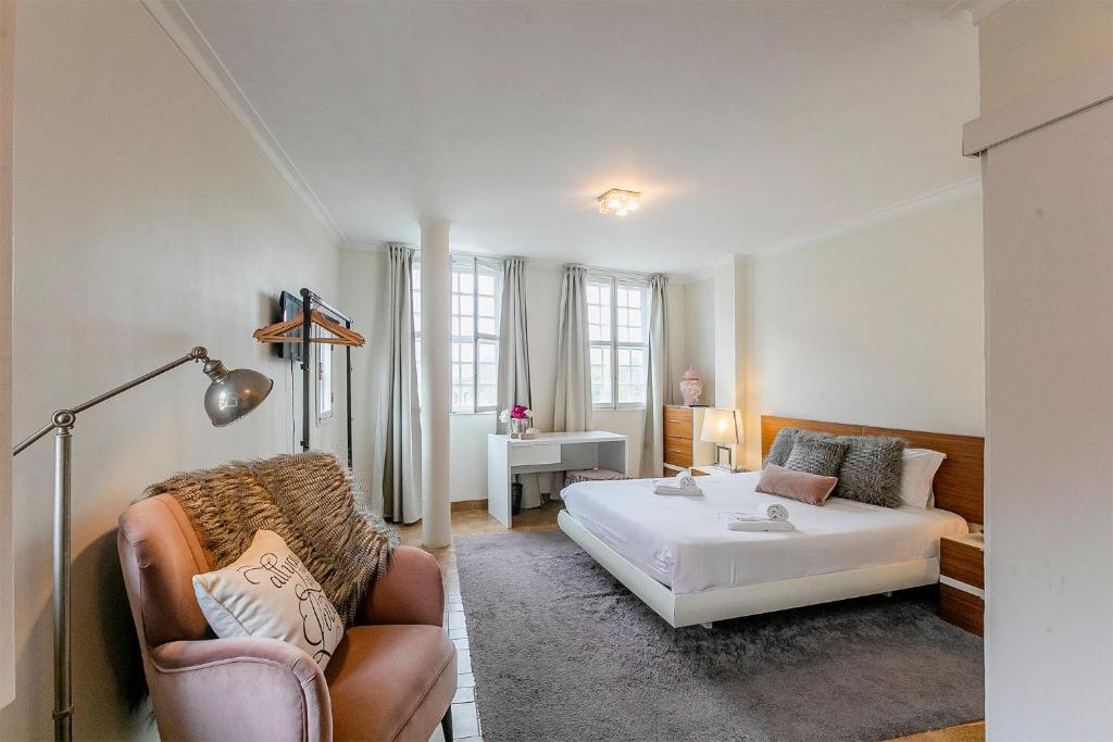 a bedroom with a bed and a couch and a chair at Spacious Duplex Apartment in the heart of Porto in Porto