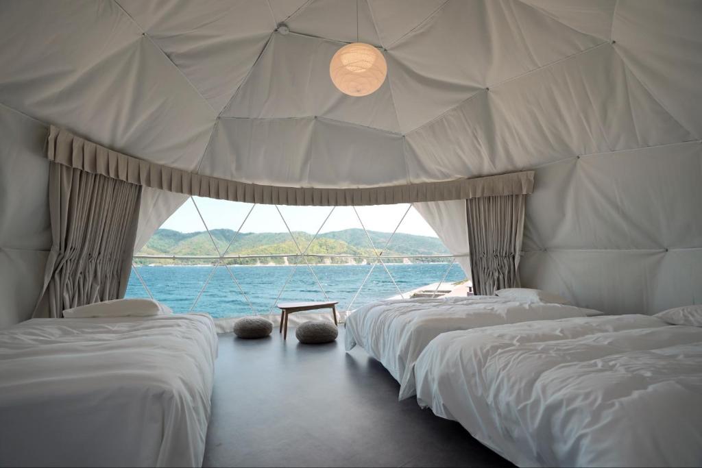 rzędu łóżek w pokoju z wodą w obiekcie TADAYOI - Sea Glamping - Camp - Vacation STAY 42099v 