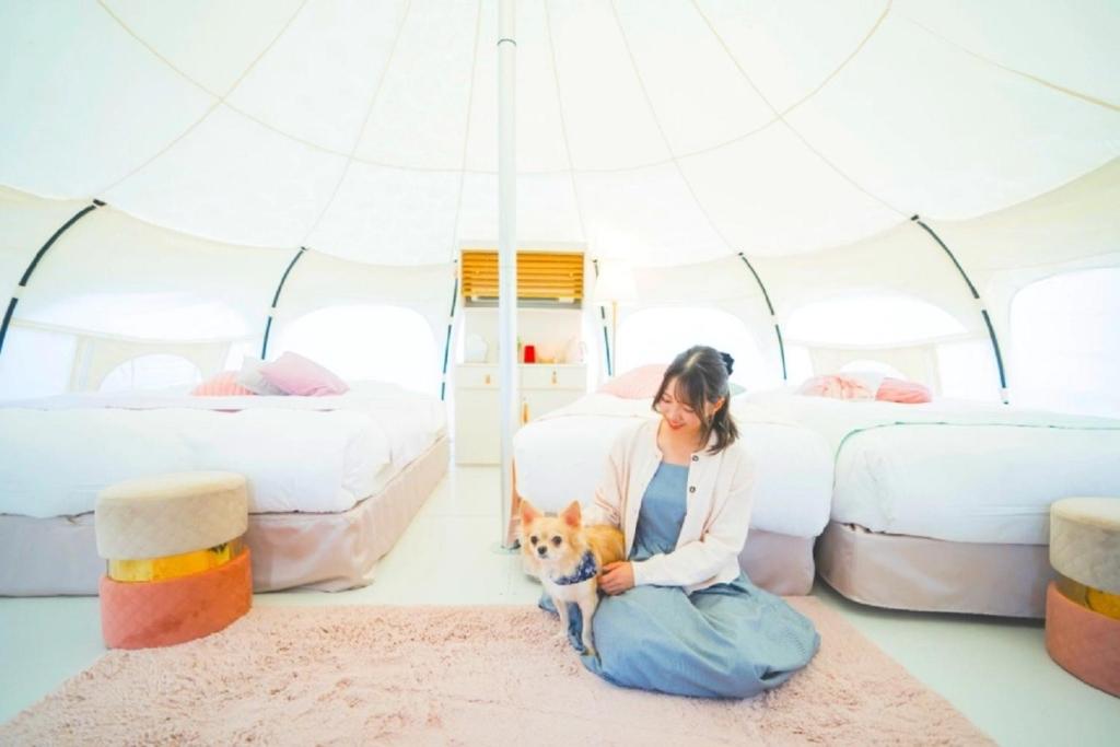 een vrouw op de vloer met een hond in een tent bij Kanonji City - Camp - Vacation STAY 42258v in Kanonji