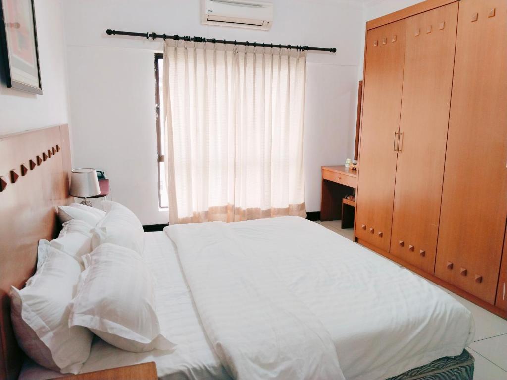 a bedroom with a bed with white sheets and a window at Maricel homestay in Kota Kinabalu