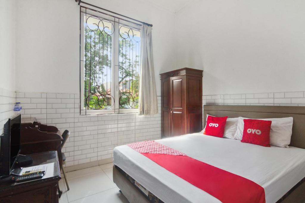 een slaapkamer met een bed met rode kussens en een televisie bij OYO 93499 Pondok Sentosa Near UPH in Jakarta