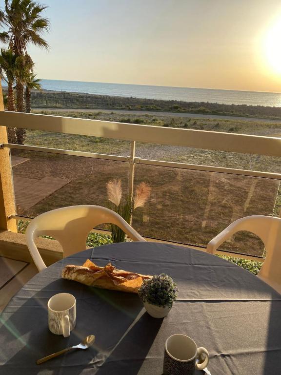 - une table avec une assiette de nourriture et une vue sur la plage dans l'établissement Appart vue mer accès plage et piscine à 30m, à Saint-Cyprien