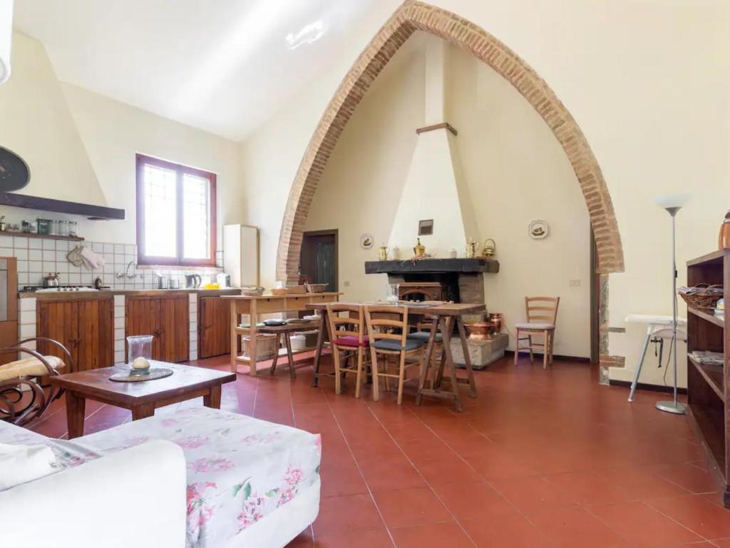 een grote woonkamer met een boog en een keuken bij Fienile in Castelnuovo Berardenga