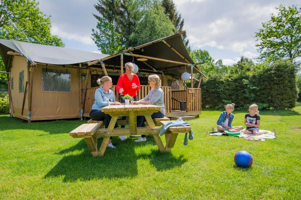 Un groupe de personnes assises à une table de pique-nique dans l'herbe dans l'établissement Glamping Drouwenerzand - Danny's Lodge, à Drouwen