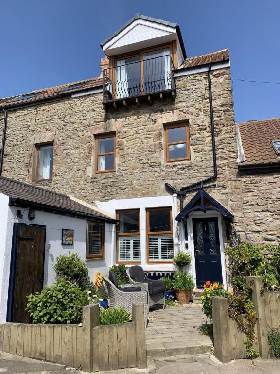 a stone house with a balcony on top of it at Sunnieside Cottage in Seahouses