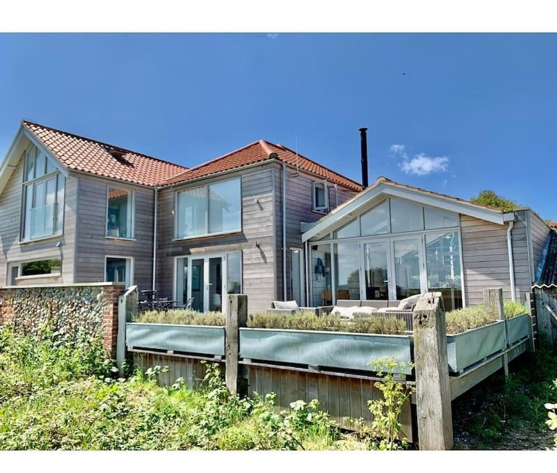 een huis met een houten hek ervoor bij Marsh Tide-SUPERB COASTAL home, breathtaking sea views in Wells next the Sea