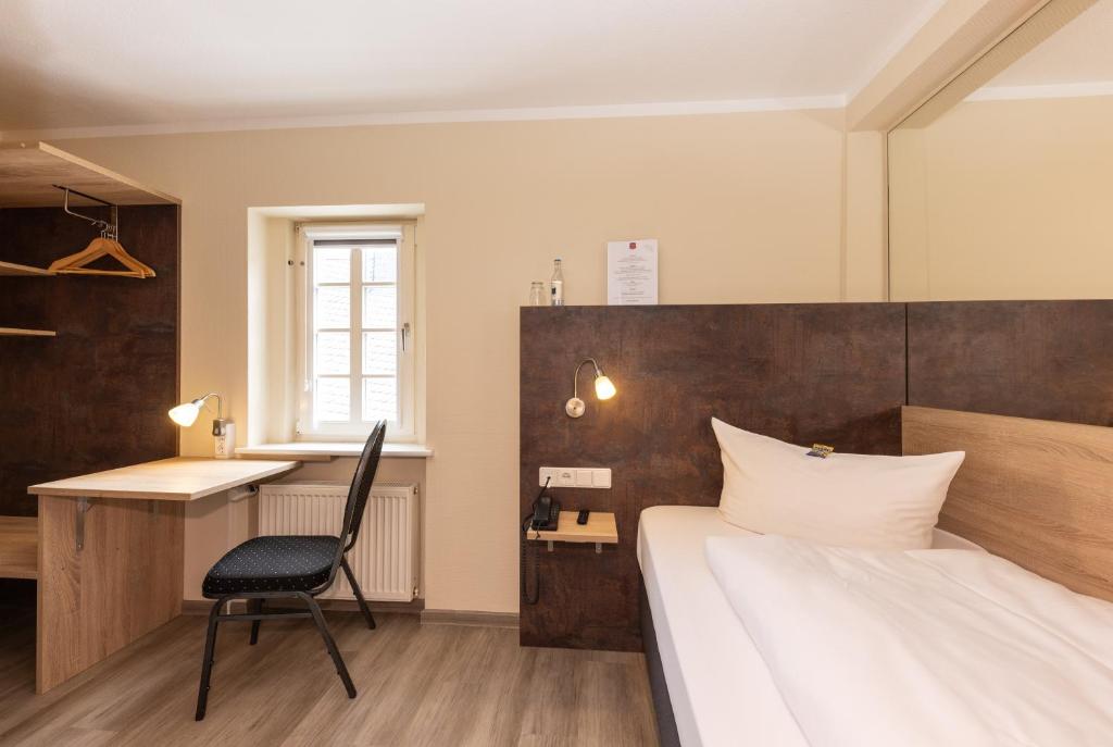 Schlafzimmer mit einem Bett, einem Schreibtisch und einem Stuhl in der Unterkunft Hotel zur Altstadt in Freudenberg