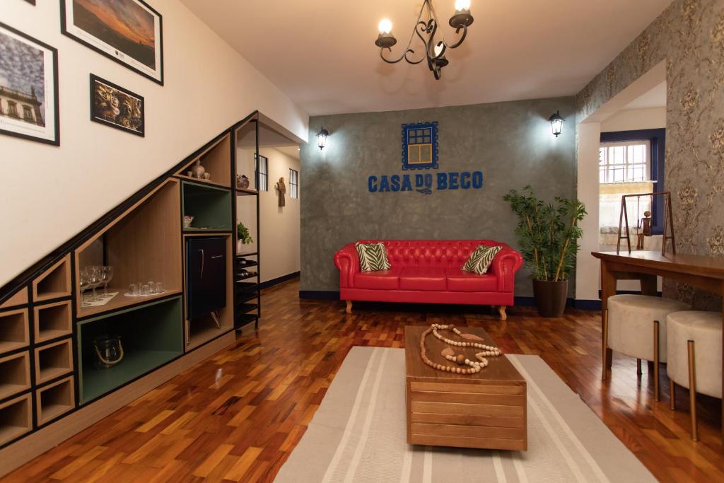 sala de estar con sofá rojo y mesa en Casa do Beco - Casa Inteira no Centro de Ouro Preto en Ouro Preto