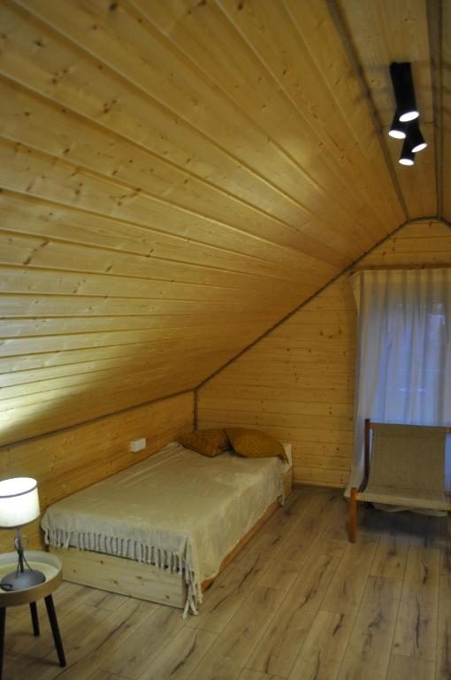 een slaapkamer met een bed in een houten kamer bij Dom Przemian Mazanówka 