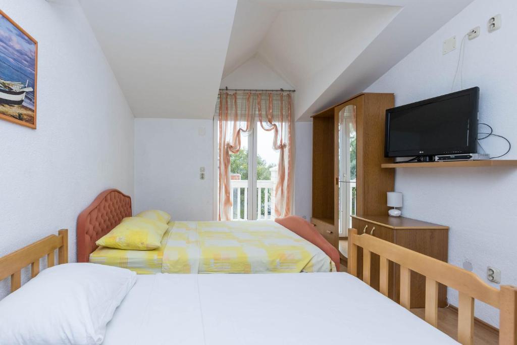 a bedroom with two beds and a tv and a window at Apartments Cipetic in Kaštela