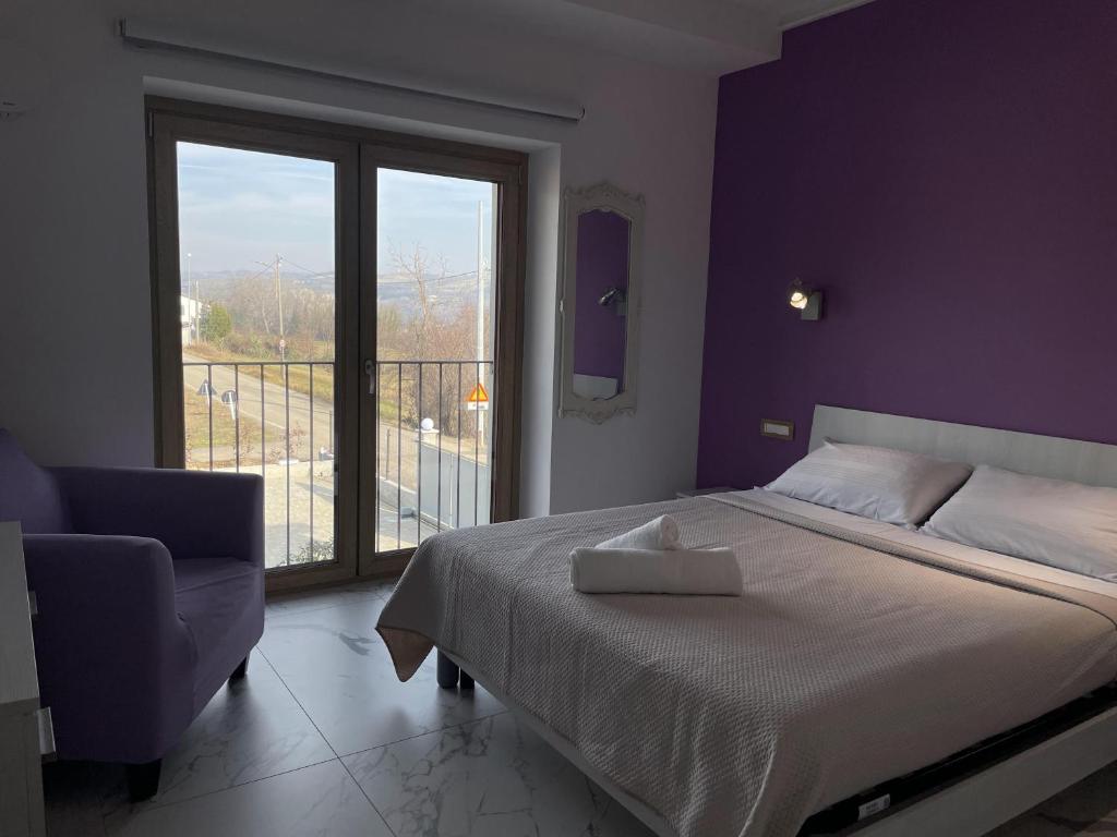 a bedroom with a bed and a chair and a window at Le Ghie in Mondovì