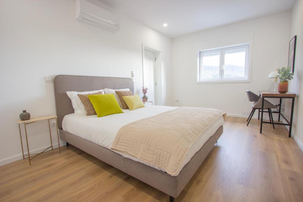 a white bedroom with a large bed with yellow pillows at Mesão Frio by Guestify in Guimarães