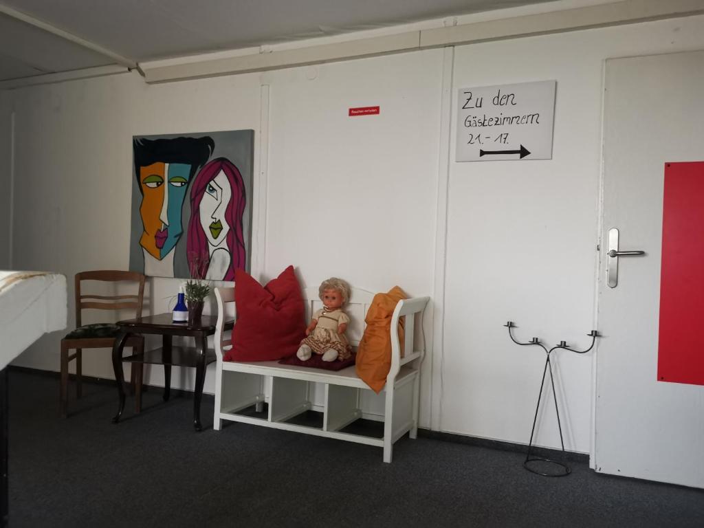 a room with a chair with a teddy bear and a painting at TWS Pension an der B1 in Magdeburg