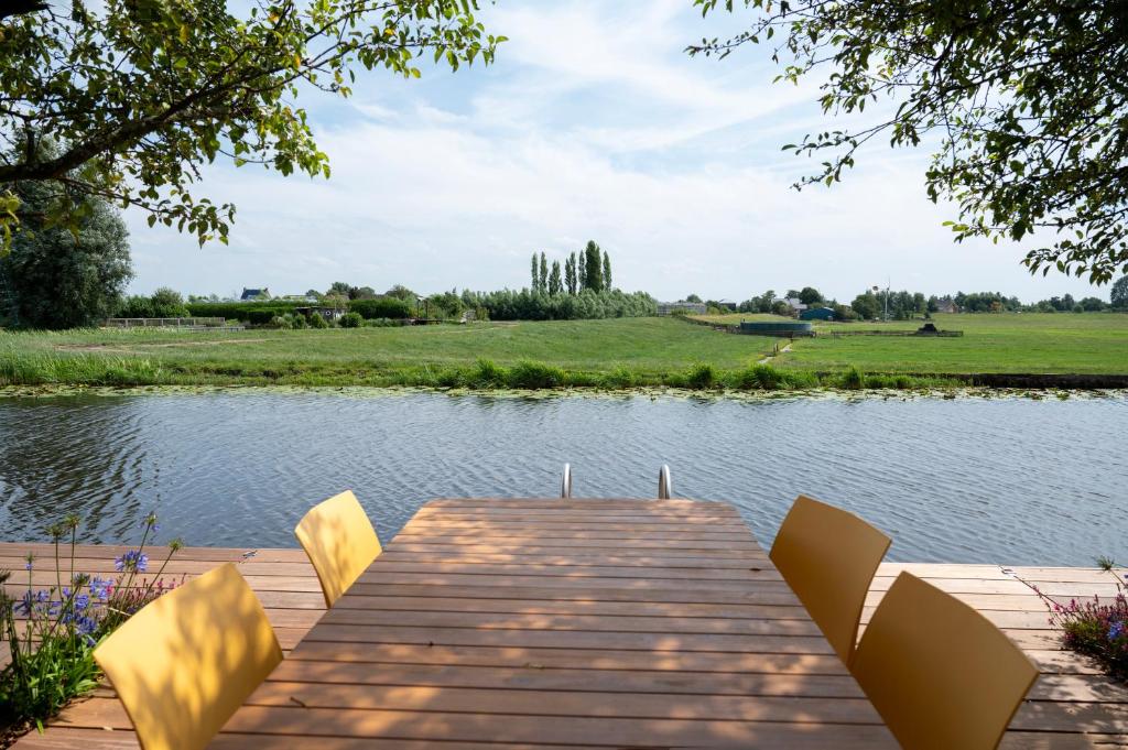un muelle de madera con sillas en un lago en 5 persons Holiday Home Comfort, en Roelofarendsveen