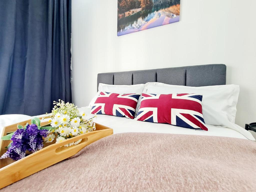a bed with british flag pillows and flowers on it at 11 Guest Comfy 3 Room Koi Kinrara Suite, IOI Puchong, Bukit Jalil Pavilion, Bukit Jalil Stadium, Sunway Pyramid, Sunway Lagoon in Kampong Baharu Sungai Way