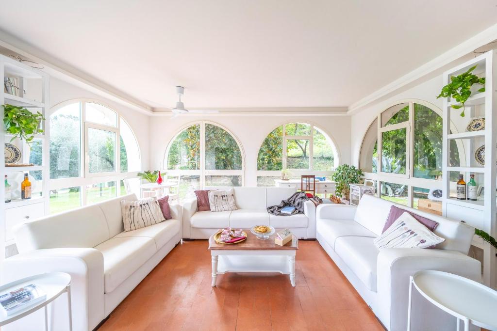 a living room with white furniture and windows at Villa Oliviana in Montecarlo
