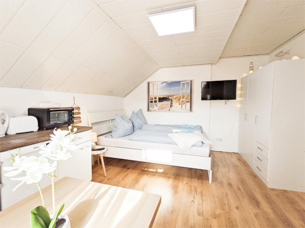 ein weißes Wohnzimmer mit einem Sofa und einem TV in der Unterkunft Urlaubsmagie - Wohlfühloase mit Pool - H5 in Sebnitz