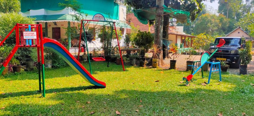 a playground with a slide in the grass at Kuttickattil Gardens Homestay in Kottayam