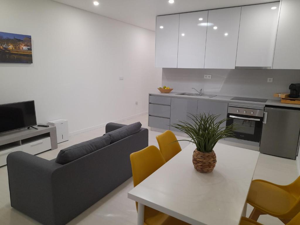 eine Küche und ein Wohnzimmer mit einem Tisch und einem Sofa in der Unterkunft Casa da Praça in Murtosa