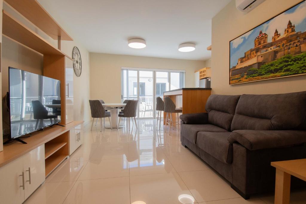uma sala de estar com um sofá e uma televisão em Venus Apartment em Sliema