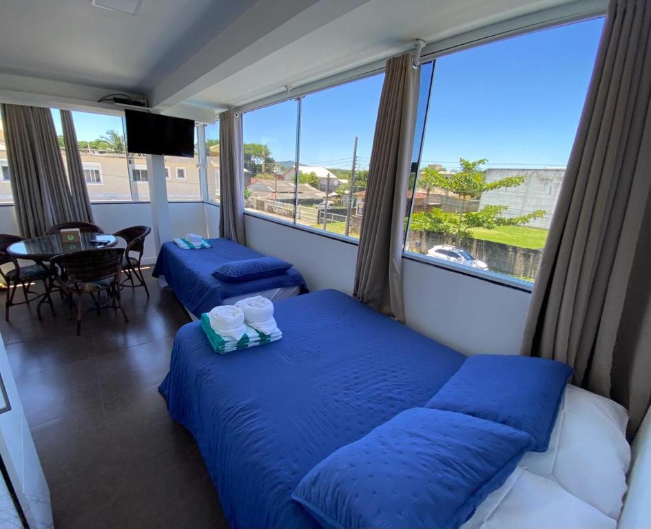 two beds in a room with a large window at Pousada da Mel - Canasvieiras Floripa in Florianópolis