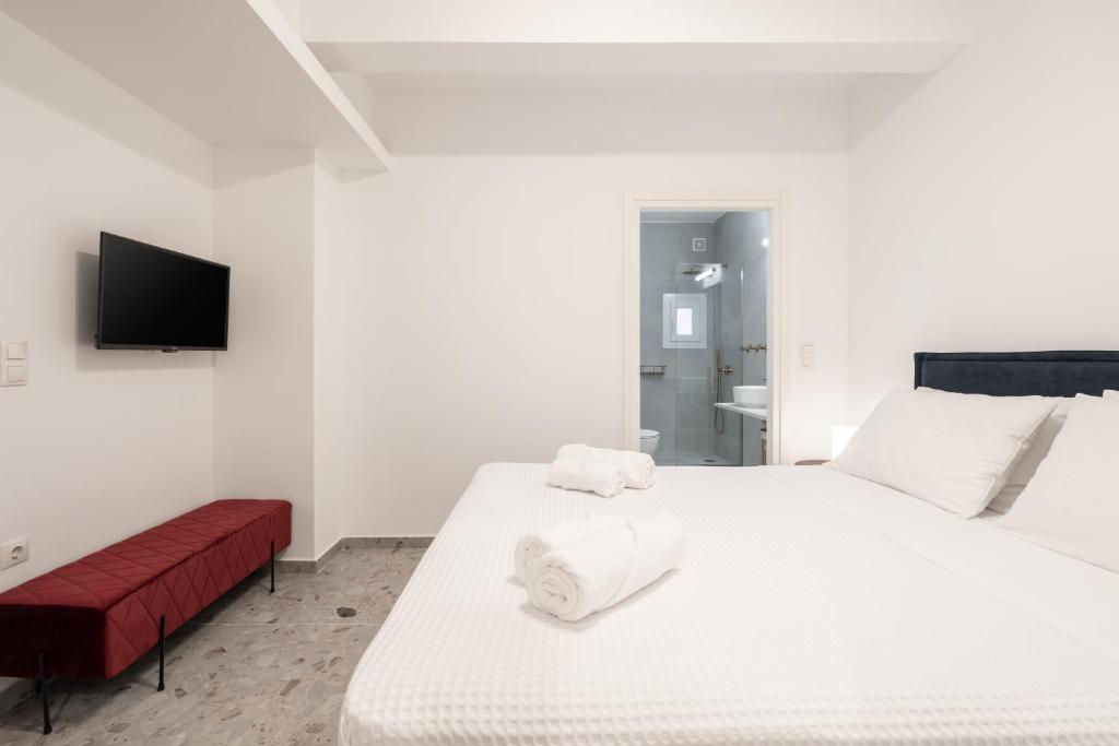 a white bedroom with a bed and a tv at Panathinea in Athens