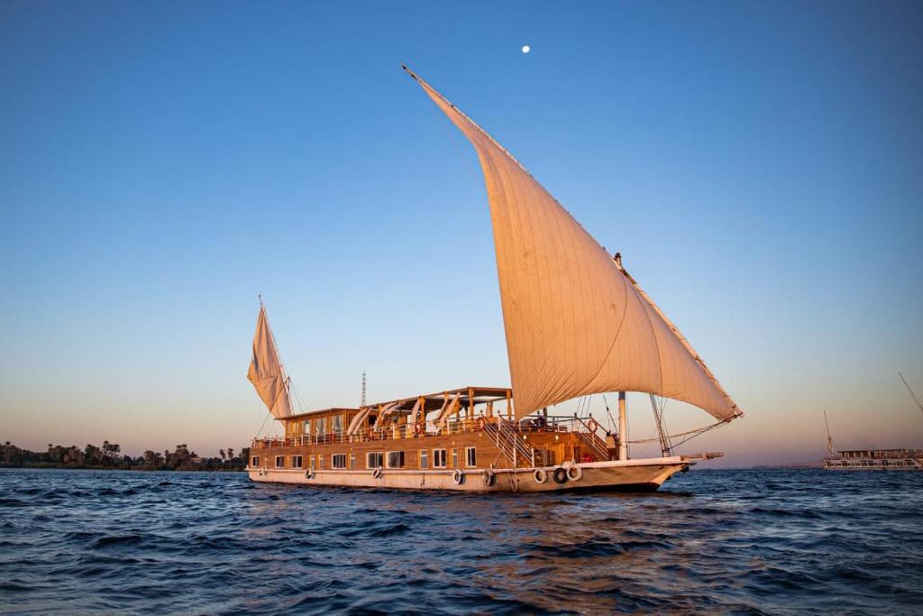 a boat with a sail in the water at Dahabiya Akhnaton Every Monday from Esna to Aswan for 4 Nights in Luxor