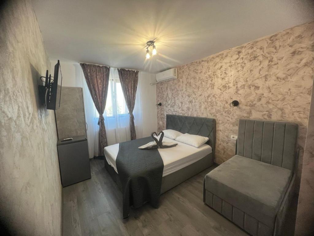 a small bedroom with a bed and a chair at Ama Boutique in Constanţa