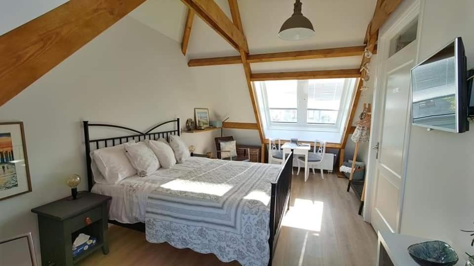 a bedroom with a large bed and a dining room at studio B&B Zeeuws licht in Westkapelle