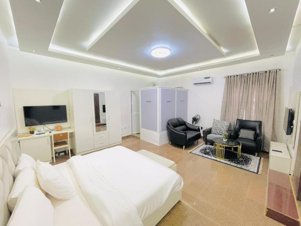 sala de estar con cama blanca y TV en Avrum Homes, en Abuja