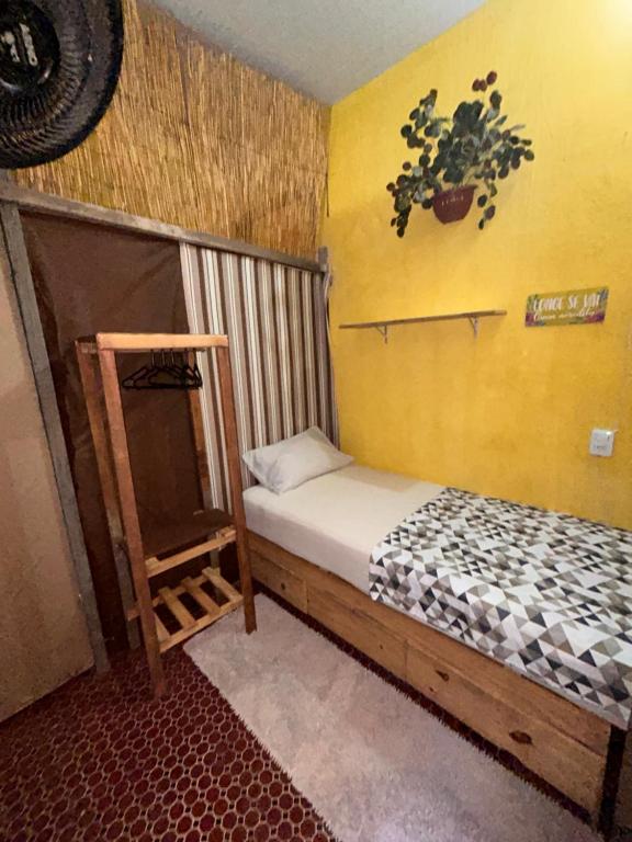 a small bedroom with a bed and a yellow wall at Casa du CéSaR in Fortaleza