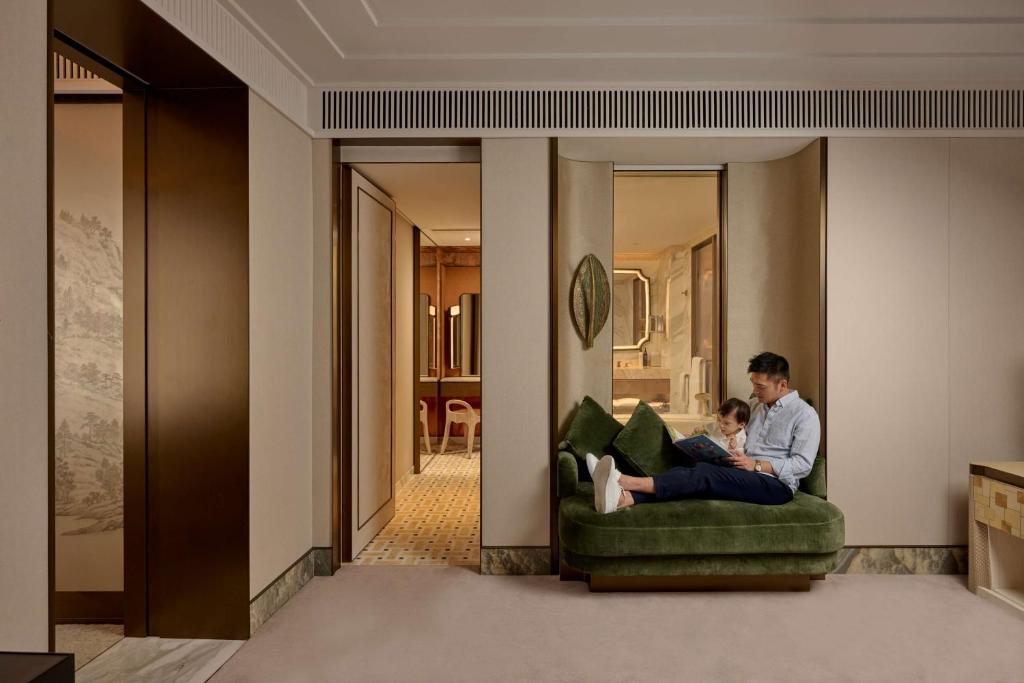 a man and a child sitting on a couch in a living room at Island Shangri-La, Hong Kong in Hong Kong