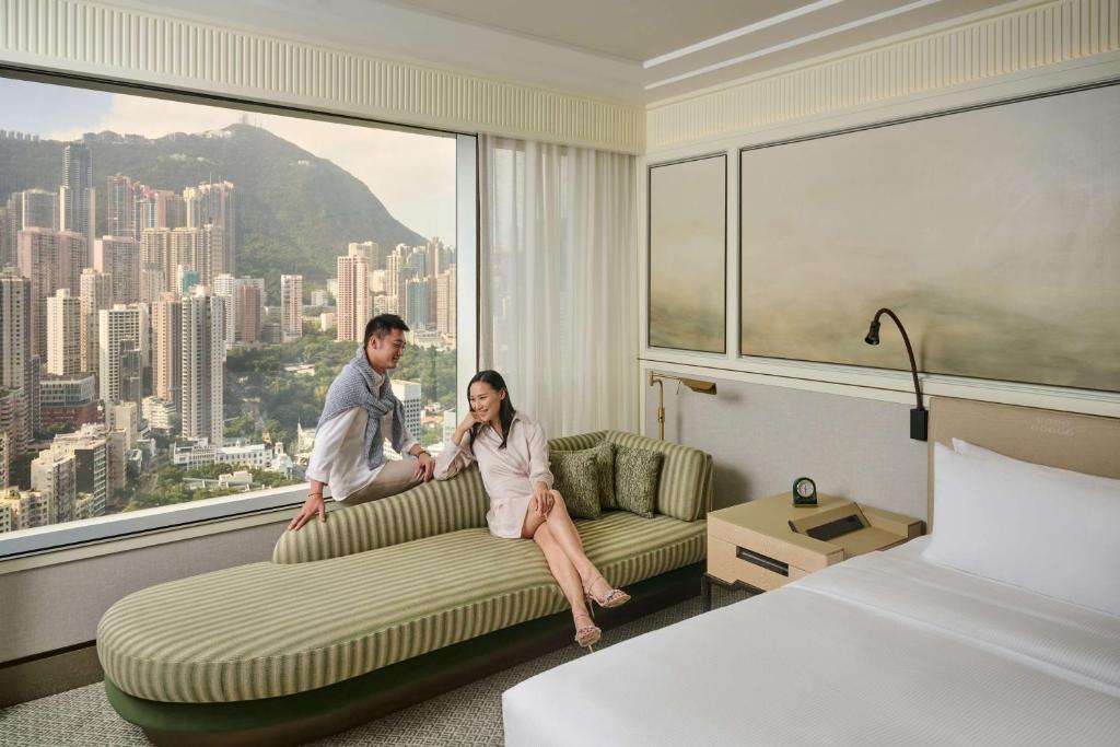 a man and woman sitting on a couch in a hotel room at Island Shangri-La, Hong Kong in Hong Kong