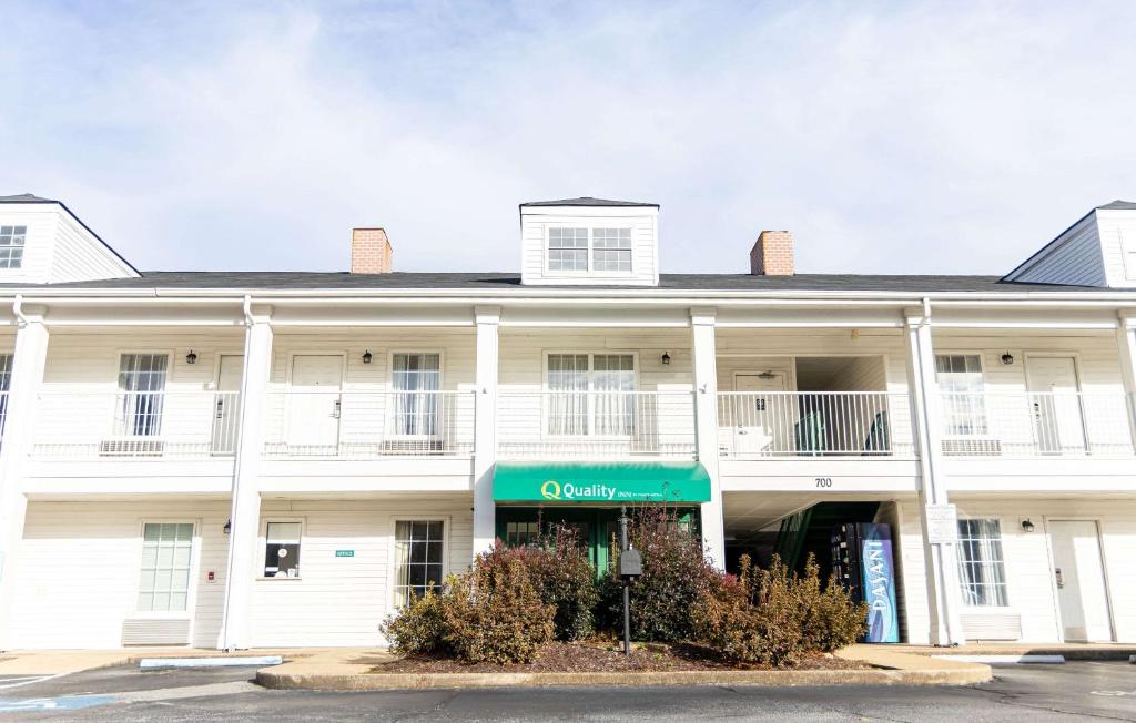 a white building with a green sign in front of it at Quality Inn in Carrollton