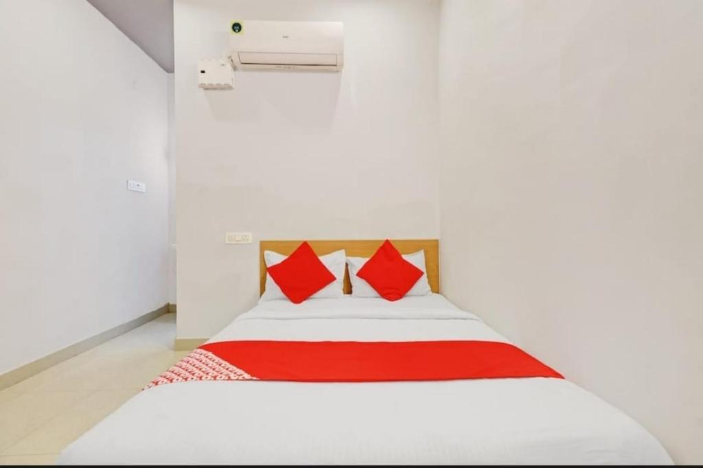 a bedroom with a white bed with red pillows at Hotel I Plaza in Tallākulam