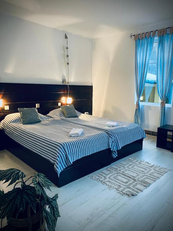 a bedroom with a large bed with blue curtains at Casa Mimi in Buşteni