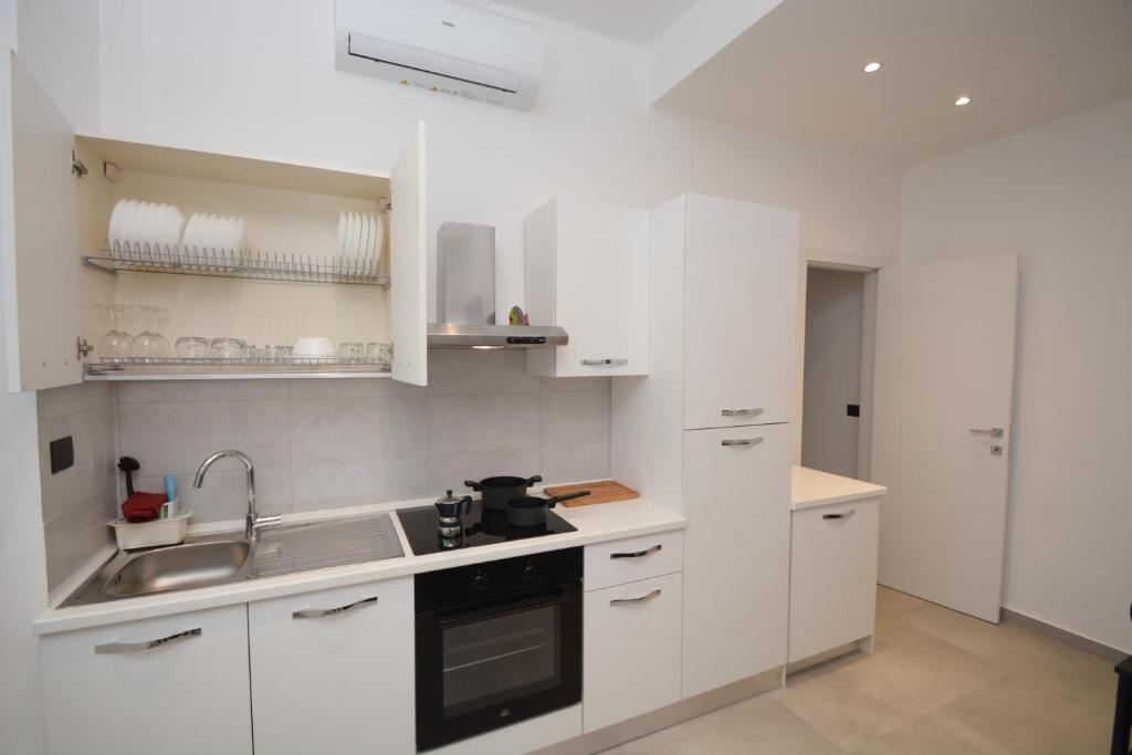 una cucina bianca con armadi bianchi e lavandino di Piazza Della Vittoria Apartment a Genova