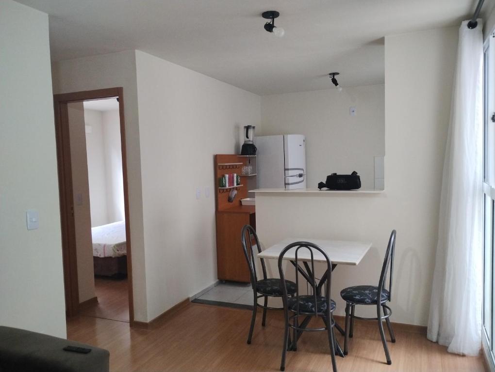 a kitchen with a table and chairs and a refrigerator at Apartamento em Santa Barbara D'oeste 