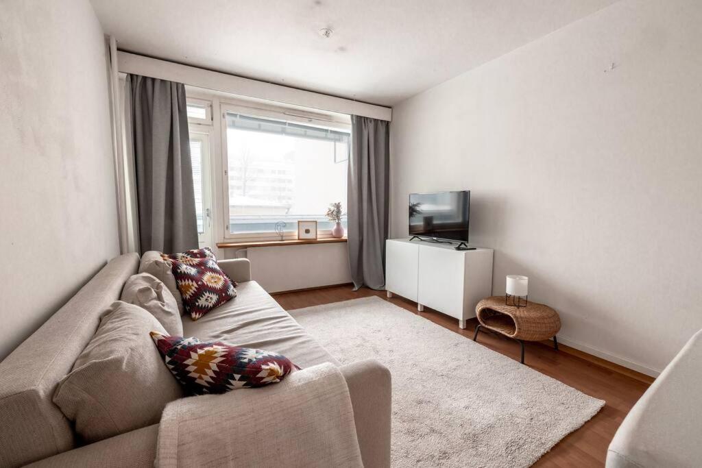 a living room with a couch and a television at 2ndhomes Cozy 1BR Apartment w/ Balcony next to tram stop in Helsinki