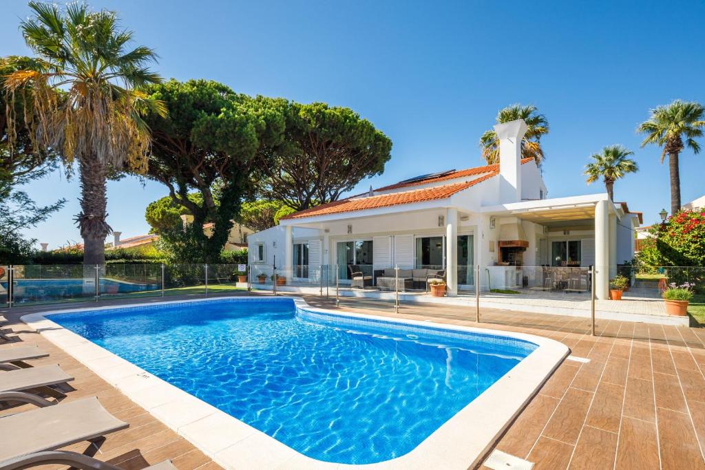 ein Pool vor einem Haus mit Palmen in der Unterkunft Charming Vale do Lobo Villa - 4 Bedrooms - Villa Quadradinhos 22 - Private Pool and Close to Amenities - Algarve in Almancil