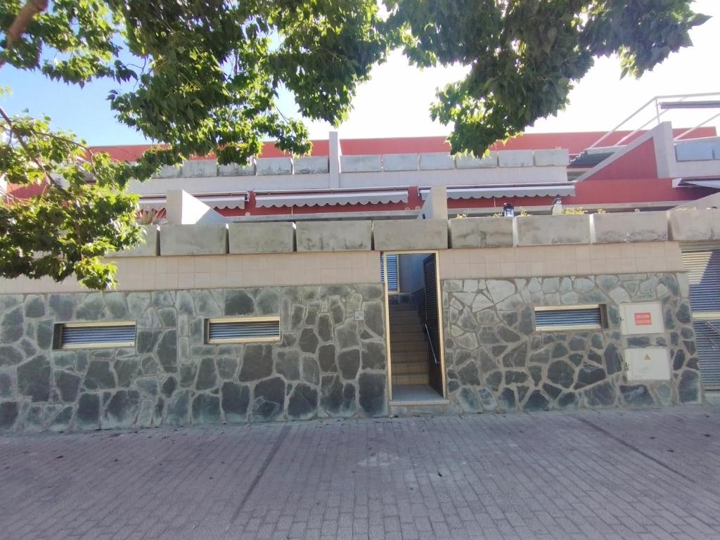 un edificio con un muro di pietra con una porta di CASA QUINO EL PARQUE a Puerto de Mogán