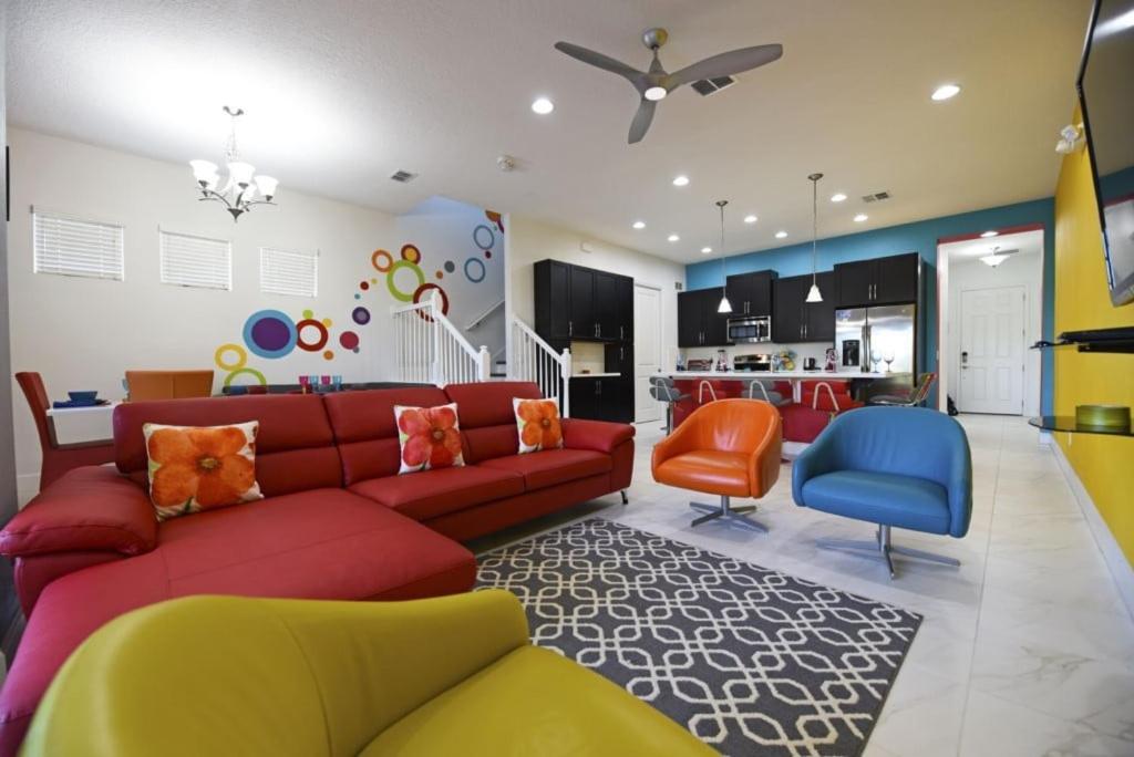 ein Wohnzimmer mit einem roten Sofa und orangefarbenen und blauen Stühlen in der Unterkunft Top Villas - Festival Resort 3 in Orlando